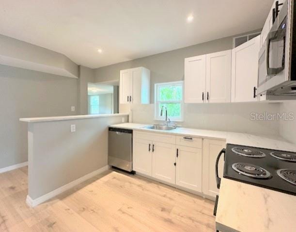 1536 S Martin Luther King Jr Ave, Clearwater, FL 33756 - kitchen featuring stainless steel appliances, a sink, white cabinets, and light wood-type flooring