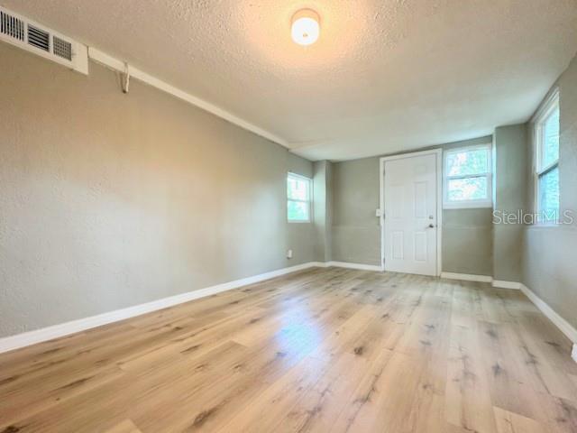 1536 S Martin Luther King Jr Ave, Clearwater, FL 33756 - empty room featuring a textured ceiling, wood finished floors, plenty of natural light, and baseboards