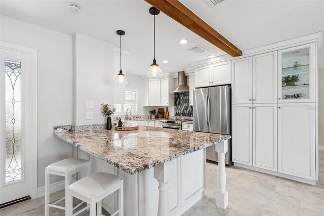 3912 Doral Dr, Tampa, FL 33634 - kitchen featuring stainless steel appliances, wall chimney exhaust hood, white cabinetry, a peninsula, and a breakfast bar area