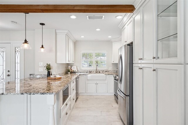 3912 Doral Dr, Tampa, FL 33634 - kitchen with stainless steel appliances, a peninsula, white cabinets, light stone counters, and recessed lighting