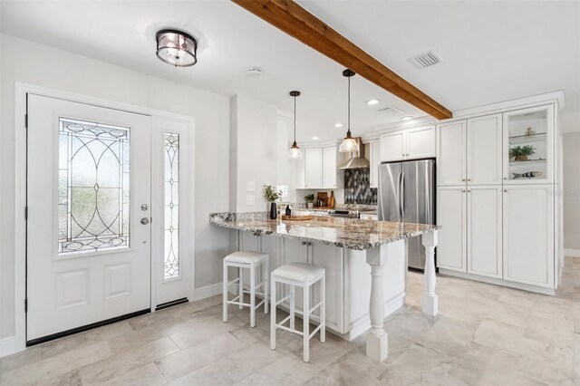 3912 Doral Dr, Tampa, FL 33634 - kitchen featuring freestanding refrigerator, a breakfast bar area, white cabinetry, light stone counters, and beam ceiling