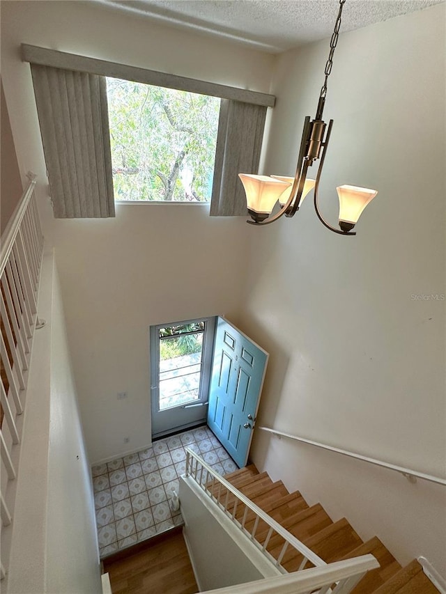 foyer entrance featuring stairs, a towering ceiling, wood finished floors, and a textured ceiling