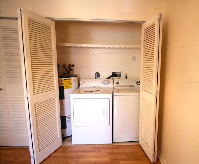laundry area with water heater, washing machine and clothes dryer, and light wood-style floors