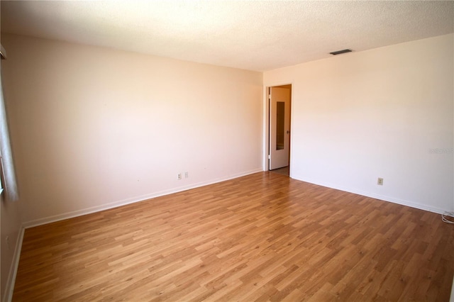 unfurnished room with light wood-style flooring, baseboards, and a textured ceiling