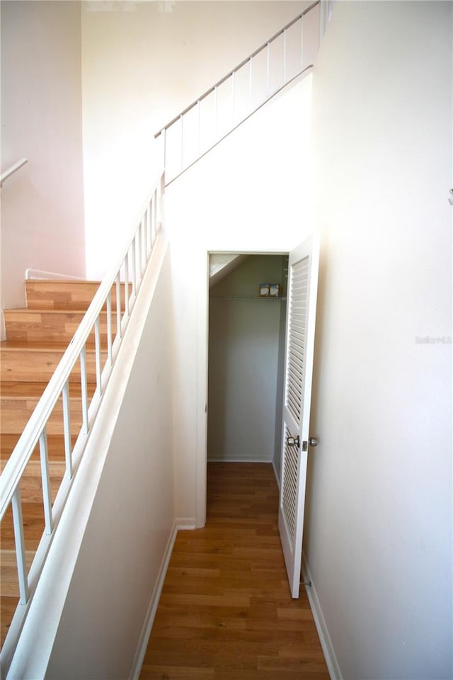 staircase featuring wood finished floors and baseboards