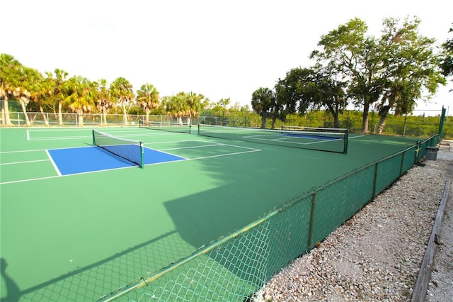 view of tennis court with community basketball court and fence