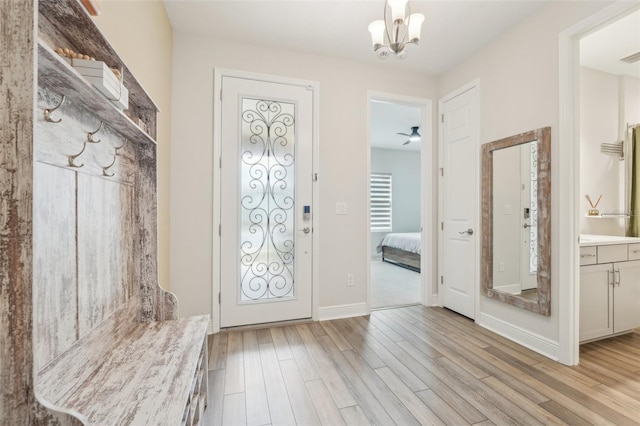 mudroom featuring light wood-style floors, a chandelier, and baseboards