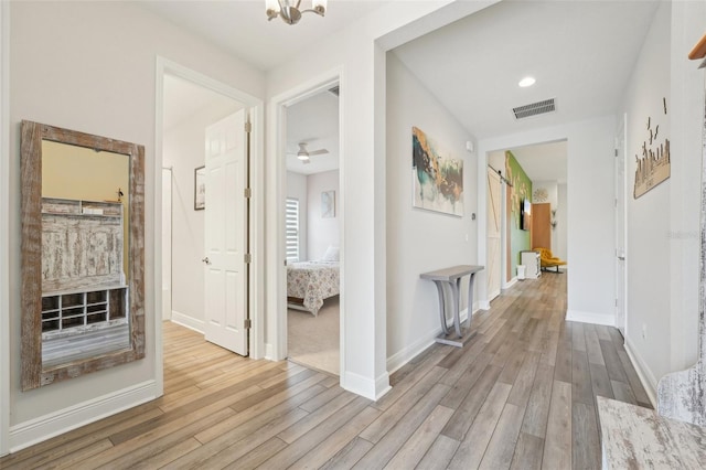 corridor featuring wood finished floors, baseboards, a chandelier, and recessed lighting