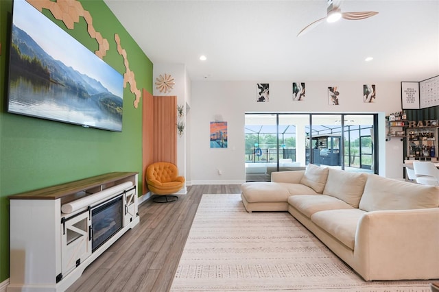 living room featuring wood finished floors, baseboards, recessed lighting, ceiling fan, and a sunroom