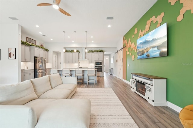 living room with ceiling fan, light wood finished floors, baseboards, and recessed lighting