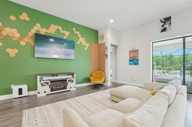 living room with baseboards, recessed lighting, wood finished floors, and an accent wall