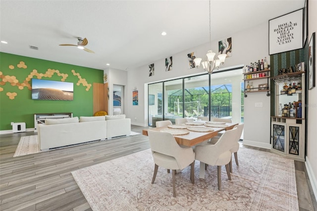 dining area with an accent wall, baseboards, a chandelier, recessed lighting, and wood finished floors