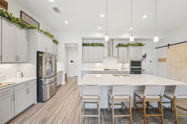 kitchen with appliances with stainless steel finishes, wall chimney exhaust hood, a sink, recessed lighting, and tasteful backsplash