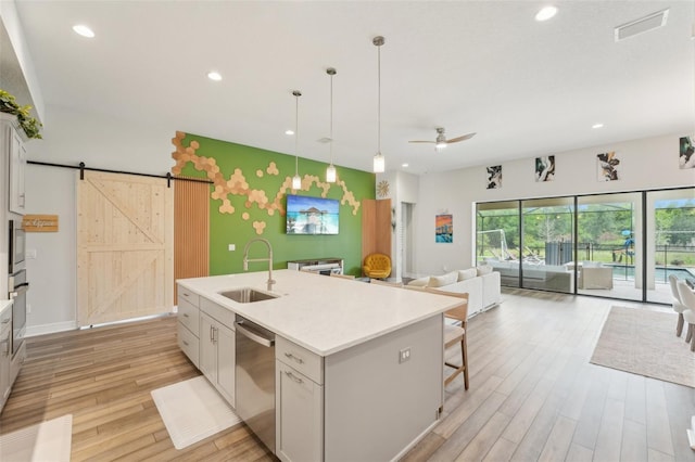 kitchen with a sink, stainless steel appliances, open floor plan, a barn door, and light wood-style floors