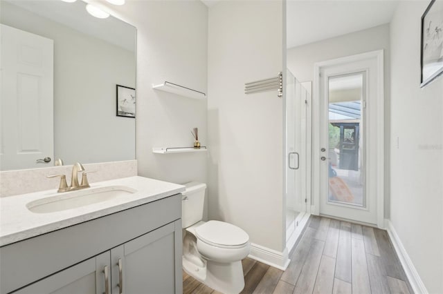 bathroom featuring toilet, a shower stall, wood finished floors, vanity, and baseboards