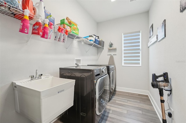 washroom featuring washer and clothes dryer, wood finished floors, and baseboards
