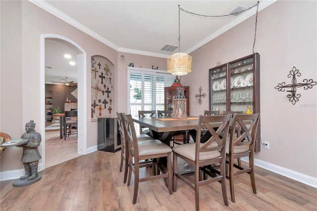 5103 Rushbrook Rd, Land O Lakes, FL 34638 - dining area with arched walkways, light wood-style flooring, crown molding, and baseboards