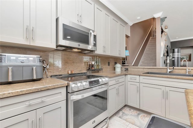 5103 Rushbrook Rd, Land O Lakes, FL 34638 - kitchen with appliances with stainless steel finishes, a sink, tasteful backsplash, light countertops, and crown molding