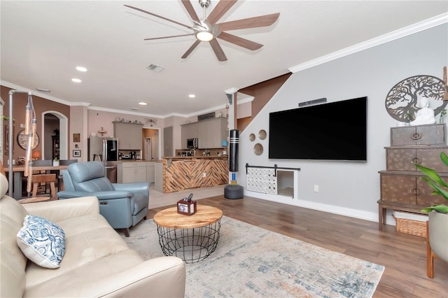 5103 Rushbrook Rd, Land O Lakes, FL 34638 - living room featuring a ceiling fan, ornamental molding, light wood-style flooring, recessed lighting, and arched walkways