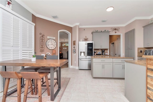 5103 Rushbrook Rd, Land O Lakes, FL 34638 - kitchen with stainless steel fridge, gray cabinets, arched walkways, crown molding, and tasteful backsplash