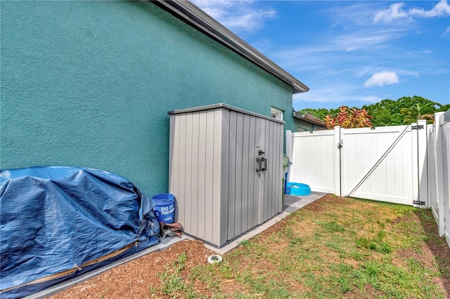 5103 Rushbrook Rd, Land O Lakes, FL 34638 - view of side of home featuring stucco siding, a gate, an outbuilding, and a shed