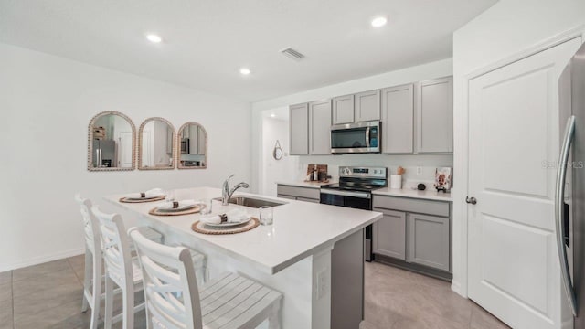 kitchen featuring appliances with stainless steel finishes, gray cabinetry, a sink, light countertops, and recessed lighting