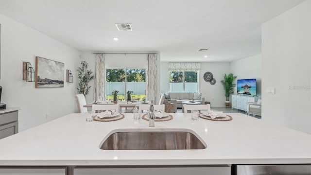 kitchen with open floor plan, light countertops, a sink, dishwasher, and a center island with sink