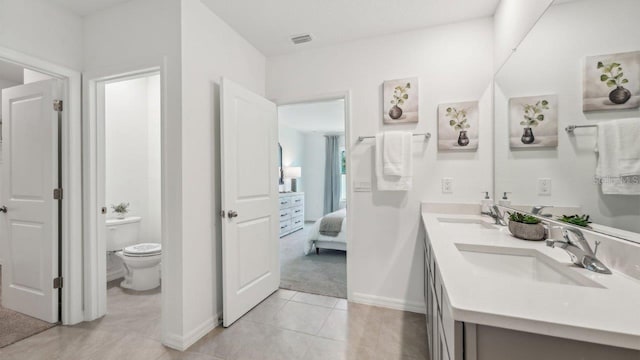 ensuite bathroom with baseboards, toilet, tile patterned flooring, and double vanity