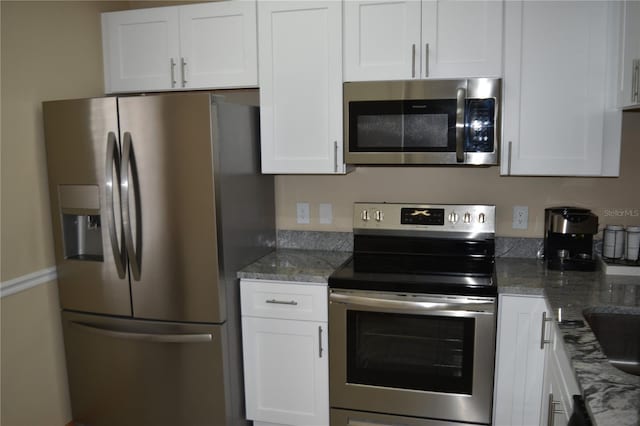 kitchen with stainless steel appliances, white cabinets, and stone counters