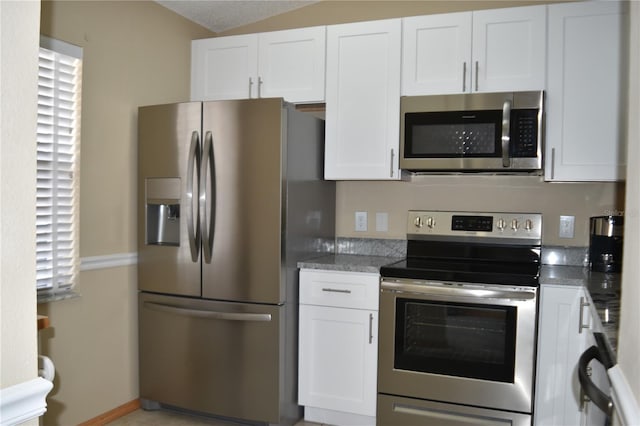 kitchen featuring stainless steel appliances, white cabinetry, and stone counters