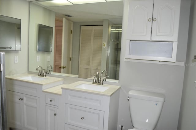 full bath with toilet, double vanity, and a closet