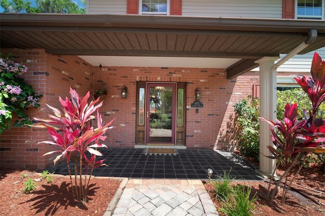 entrance to property featuring covered porch and brick siding