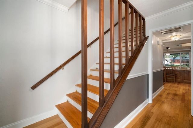 staircase featuring ornamental molding, hardwood / wood-style flooring, and baseboards