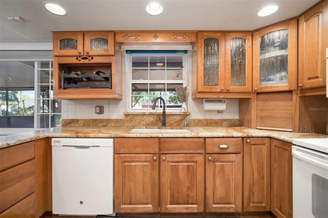 kitchen featuring dishwasher, a sink, healthy amount of natural light, light stone countertops, and recessed lighting