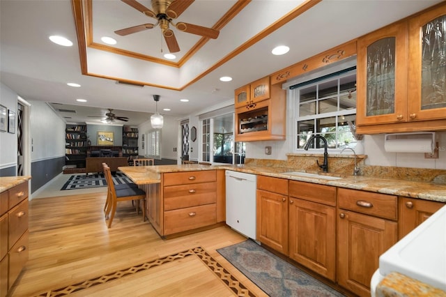 kitchen with ceiling fan, dishwasher, a sink, a tray ceiling, and a peninsula