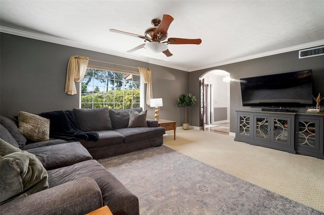 living room with arched walkways, carpet, crown molding, ceiling fan, and baseboards
