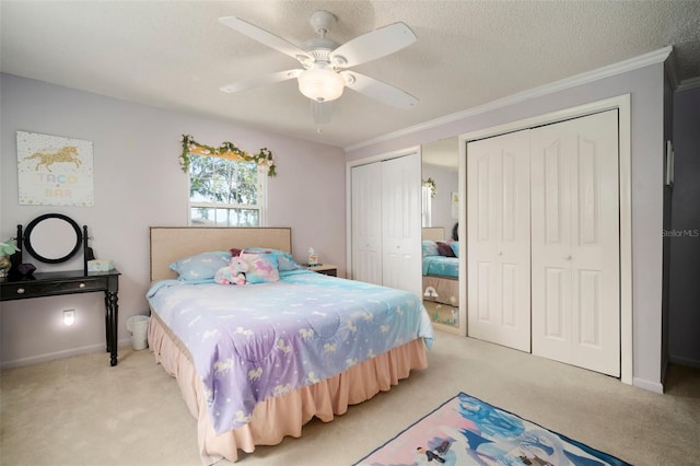 bedroom featuring multiple closets, light colored carpet, crown molding, a ceiling fan, and a textured ceiling