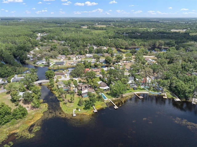 aerial view of property's location featuring a forest, a large body of water, and nearby suburban area