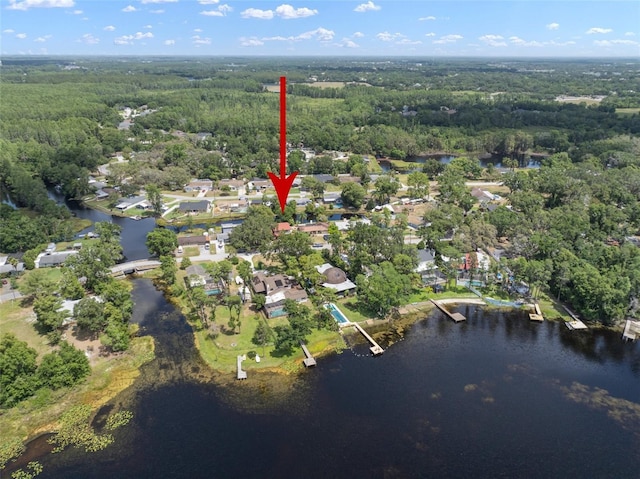 aerial view of property and surrounding area with a forest, a nearby body of water, and nearby suburban area