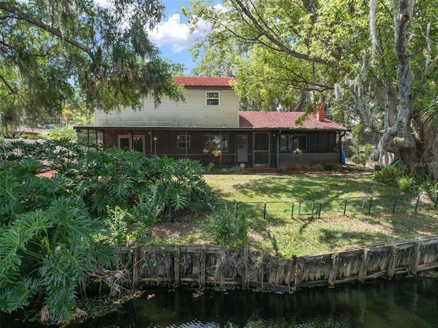 back of property featuring a sunroom, a water view, and a chimney