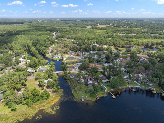 aerial view of property's location featuring a heavily wooded area, a large body of water, and nearby suburban area