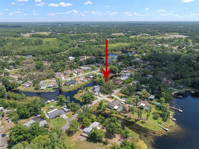 aerial view of property and surrounding area with a large body of water, nearby suburban area, and a heavily wooded area