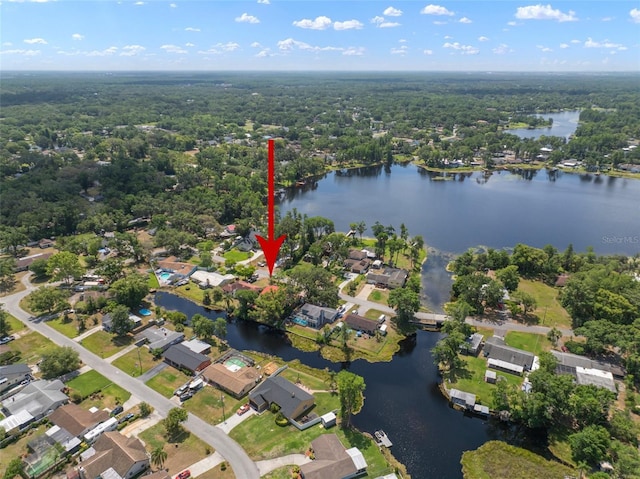 view of property location with a large body of water, a heavily wooded area, and nearby suburban area