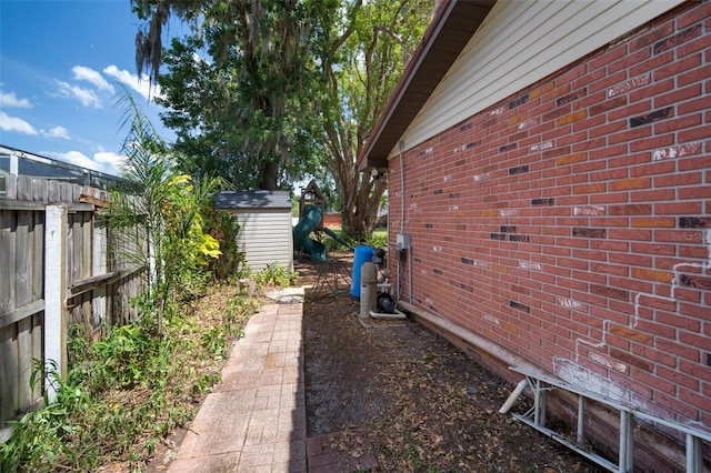 view of home's exterior with a storage shed, brick siding, an outbuilding, and fence