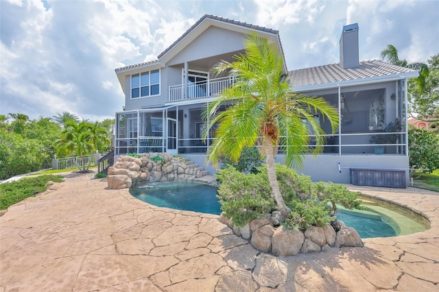 outdoor pool featuring a sunroom, fence, and a patio area