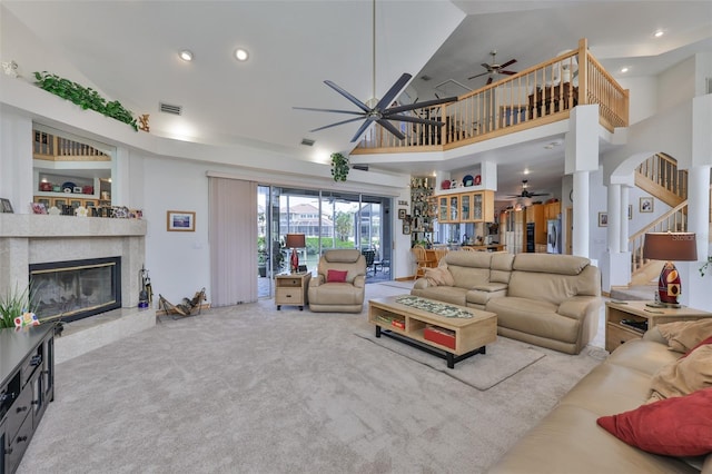 living room with ceiling fan, a high end fireplace, a towering ceiling, carpet, and recessed lighting