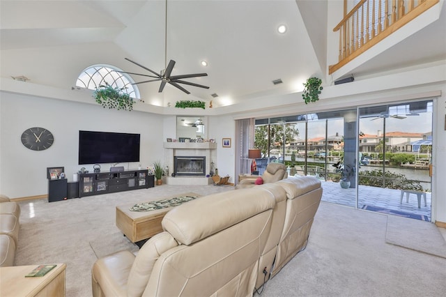 living area with a ceiling fan, carpet floors, high vaulted ceiling, a high end fireplace, and healthy amount of natural light