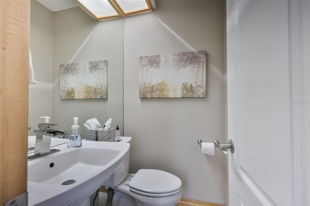 bathroom featuring a sink, toilet, and a skylight