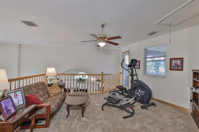 exercise area featuring attic access, a ceiling fan, carpet floors, and baseboards