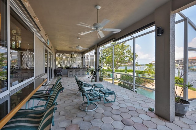 sunroom / solarium with a water view and a ceiling fan